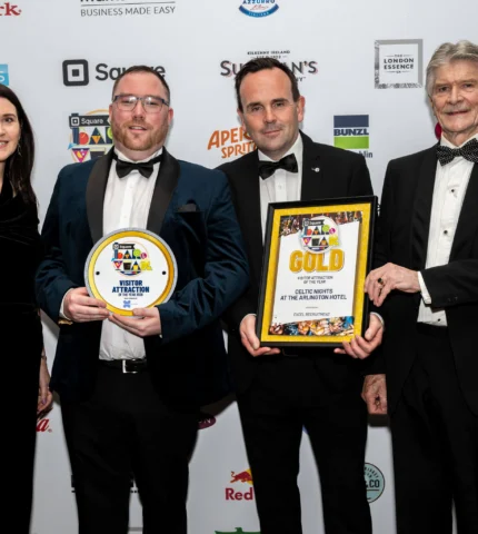 Four people in formal attire holding awards at a hotel event.