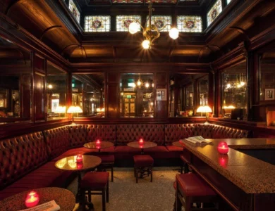 Elegant vintage bar with plush red seating, dim lighting, and glowing lamps.