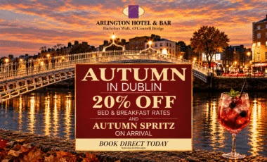 Evening riverside view of Ha'penny Bridge with autumn lights, promotional sign reading "AUTUMN IN DUBLIN 20% OFF BED & BREAKFAST RATES" and a spritz cocktail in foreground