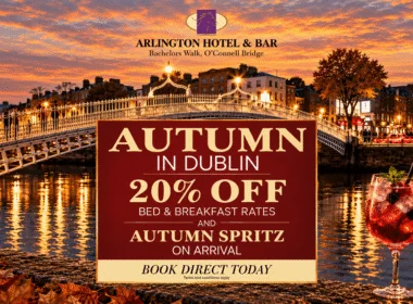 Evening riverside view of Ha'penny Bridge with autumn lights, promotional sign reading "AUTUMN IN DUBLIN 20% OFF BED & BREAKFAST RATES" and a spritz cocktail in foreground