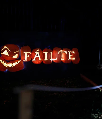 Illuminated carved pumpkins at night spelling "FÁILTE" with a smiling jack‑o'lantern, welcoming guests to the hotel grounds