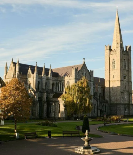 Sunlit St Patrick’s Cathedral and peaceful park with benches, fountain and visitors strolling nearby