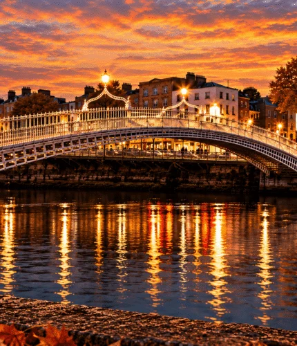 Evening view of Ha'penny Bridge over the Liffey with city lights reflected and a berry cocktail in foreground