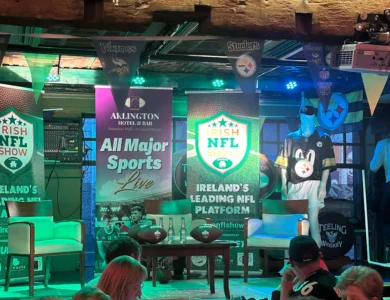 Guests enjoying drinks at Arlington Hotel and Bar with sports memorabilia and banners.