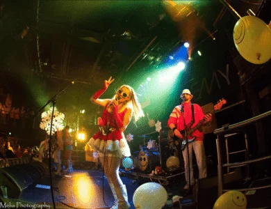 Band performing lively music on stage with festive lights and decorations.